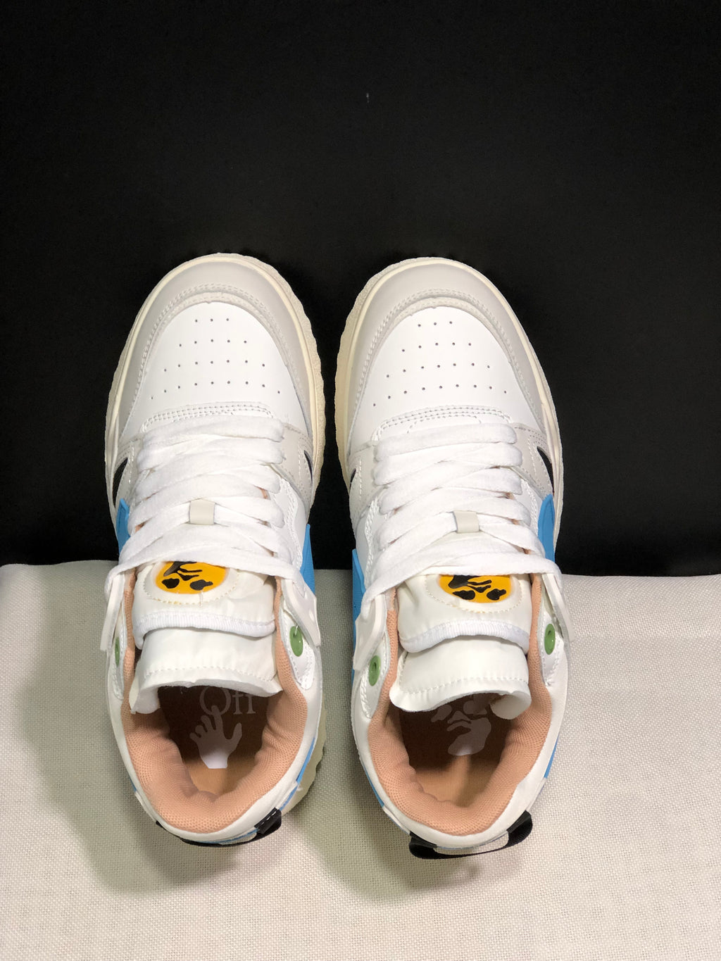 Top view showing white laces, perforated toe panels, colored tongue labels, and contrasting interior details.