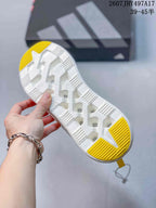 Underside view showing the white segmented outsole with textured grooves and yellow traction sections.
