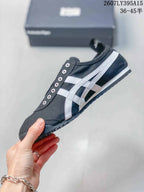 Side view of the black sneaker showing white Onitsuka Tiger stripes, metal eyelets, a padded collar, and a low-profile sole.