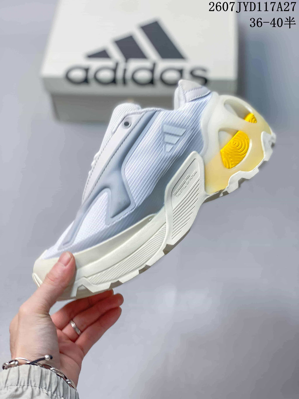 Side view showing layered panels, adidas branding, sculpted midsole, and yellow heel detail.