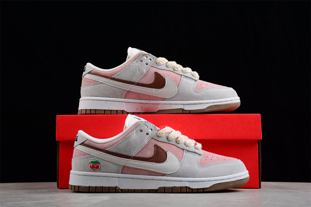 Side view of the sneakers displayed on a red shoebox, showing the layered panels and cherry detail.