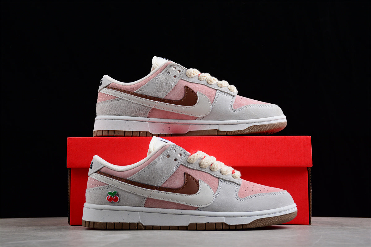 Side view of the sneakers displayed on a red shoebox, showing the layered panels and cherry detail.