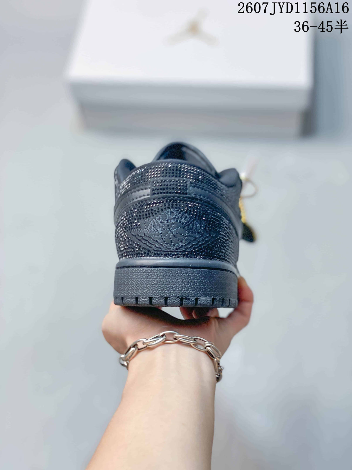 Rear view of the black sneaker showing the embellished heel panel and textured outsole.