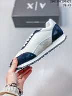 Side profile showing the white upper, navy overlays, layered midsole, and textured outsole.