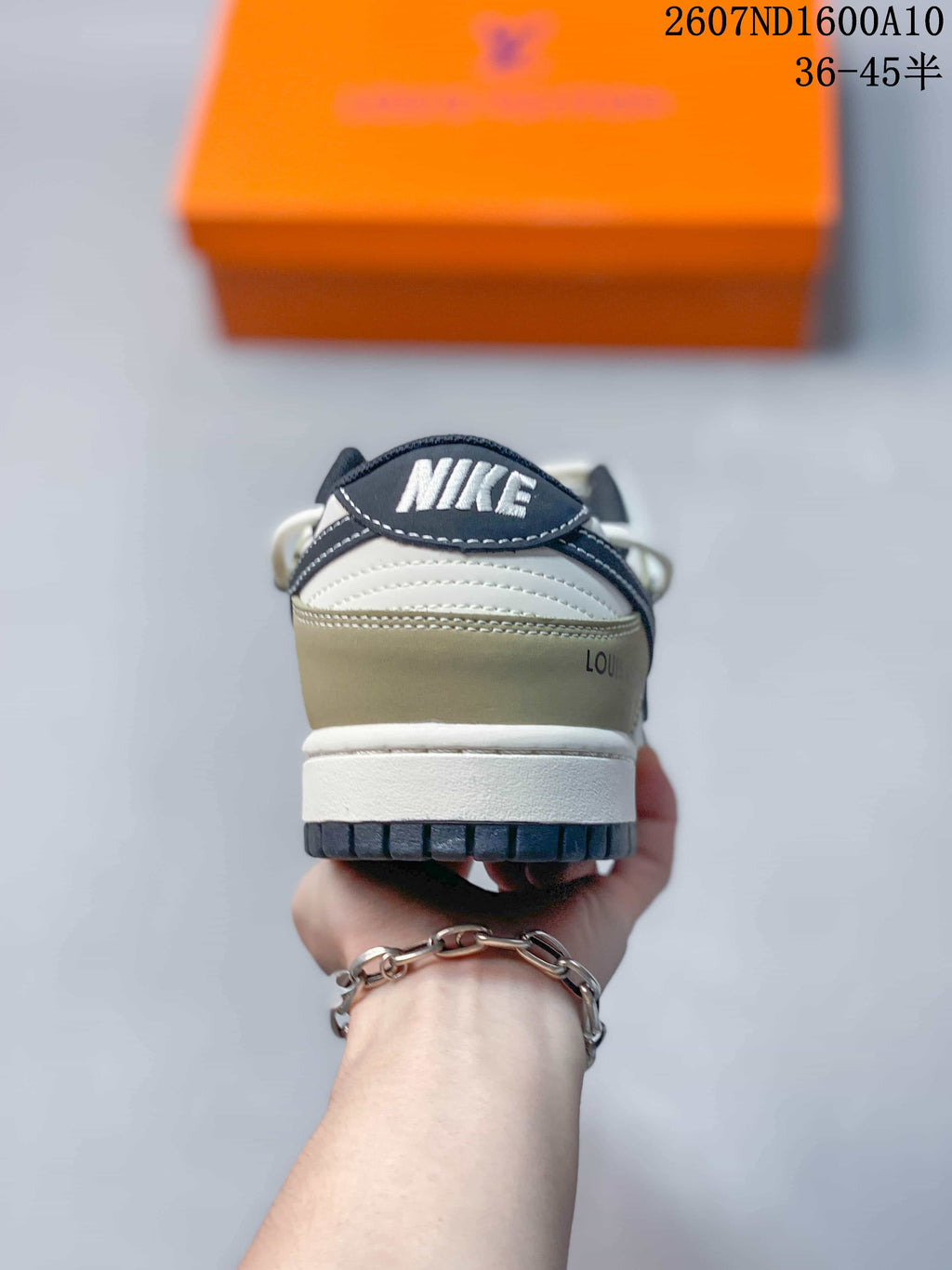 Rear view of the sneaker showing a layered heel, white midsole, dark outsole, and visible branding details.
