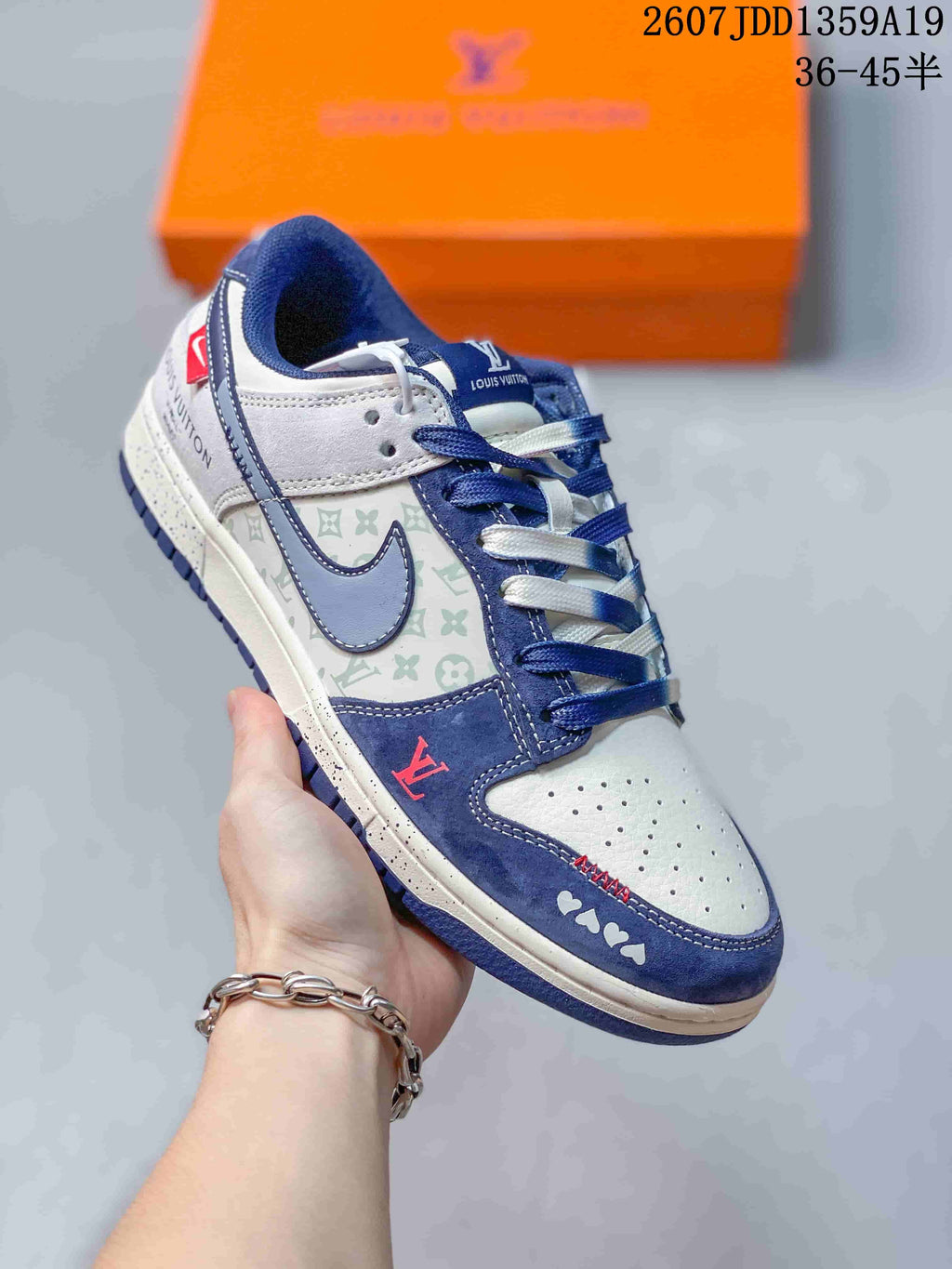 Angled close-up of the white and navy sneaker showing the patterned side panel, contrast swoosh-shaped overlay, red accent, and branded details.