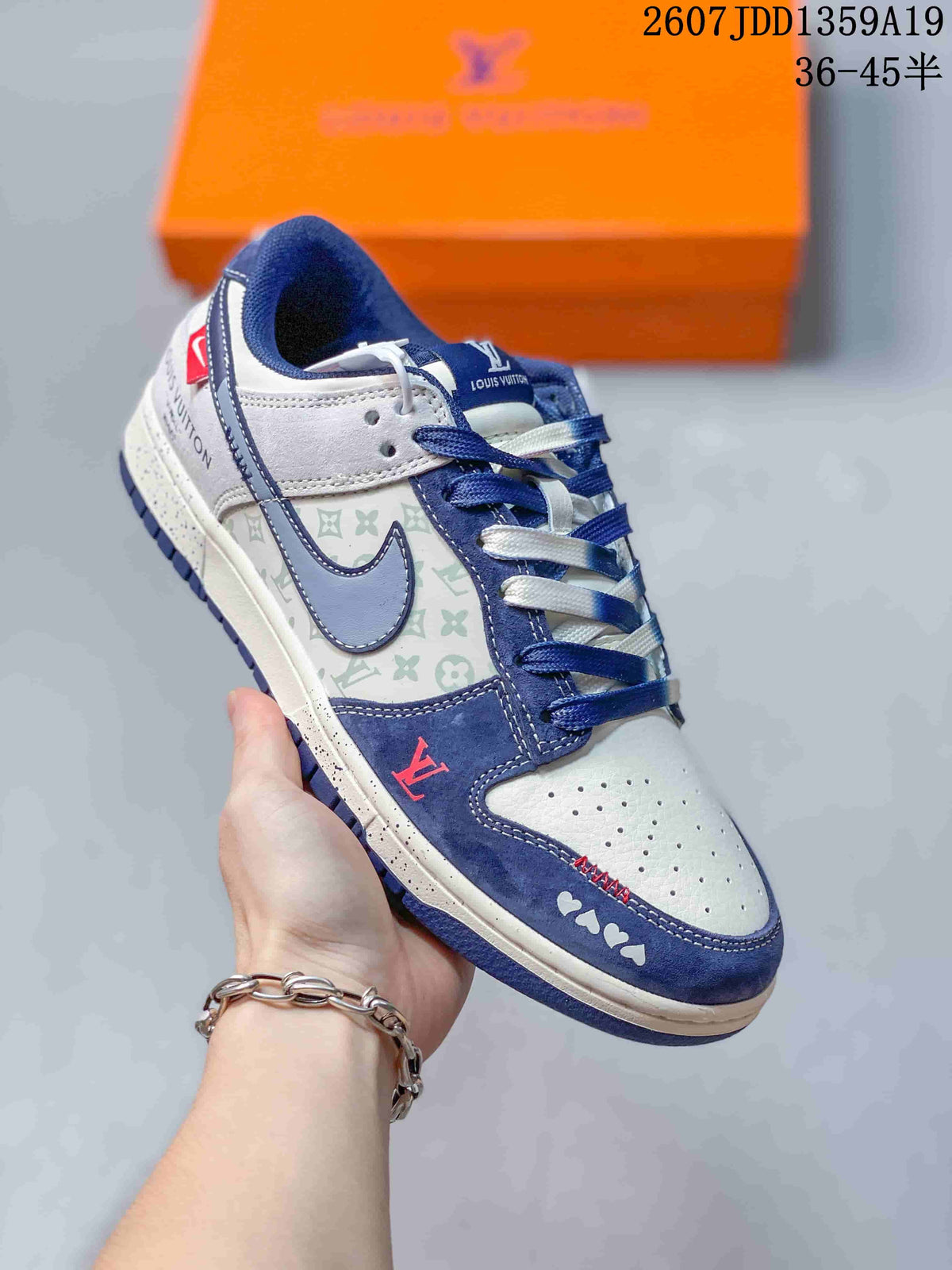 Angled close-up of the white and navy sneaker showing the patterned side panel, contrast swoosh-shaped overlay, red accent, and branded details.