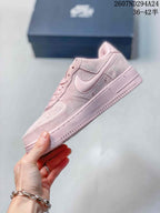 Side profile of the soft pink low-top sneaker showing the Swoosh, layered panels, and textured outsole.