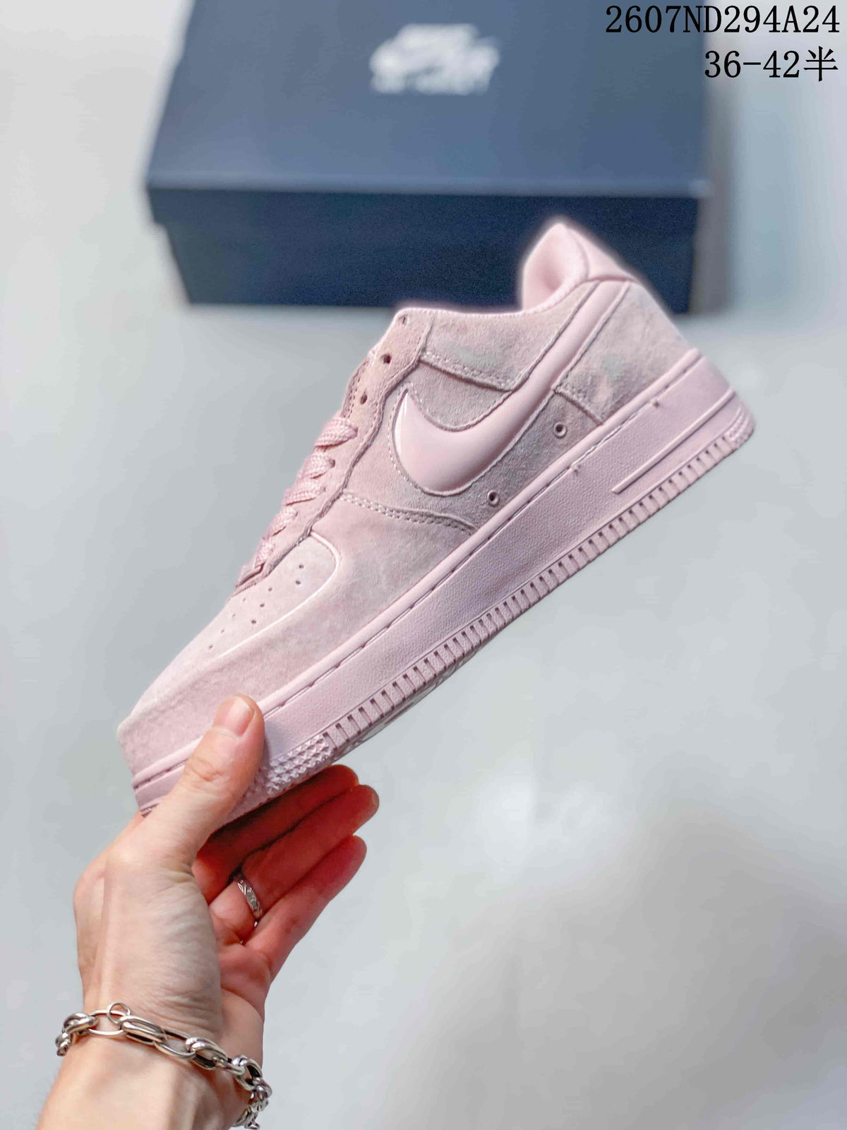 Side profile of the soft pink low-top sneaker showing the Swoosh, layered panels, and textured outsole.
