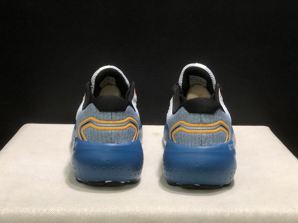 Rear view of both Brooks Glycerin 21 sneakers showing the blue heel section and layered orange and gray heel detailing.