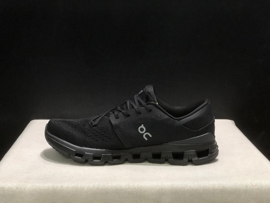 Side profile of a black On Cloud X4 shoe showing the low-top shape and segmented outsole.