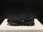 Side profile of a black On Cloud X4 shoe showing the low-top shape and segmented outsole.