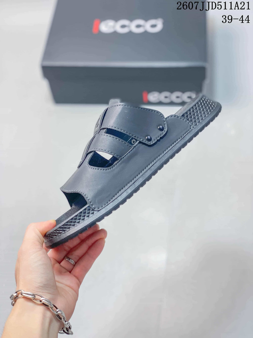 Side view of a gray open-toe sandal showing layered adjustable straps and the patterned outsole.