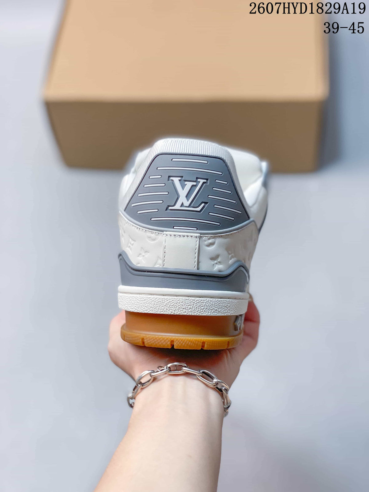 Rear view of the sneaker showing the gray heel panel, Louis Vuitton emblem, embossed side detailing, white midsole, and gum outsole.