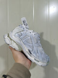 White Runner sneaker shown from a three-quarter side angle, highlighting layered panels, mesh sections, and the sculpted sole.