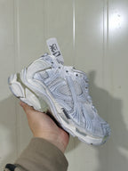 White Runner sneaker shown from a three-quarter side angle, highlighting layered panels, mesh sections, and the sculpted sole.