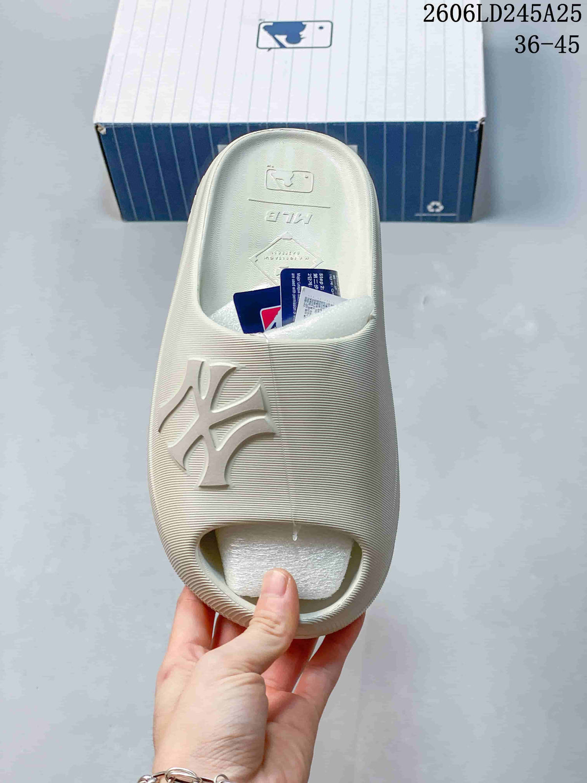 Top view of an off-white slide sandal showing the broad strap and raised MLB logo.