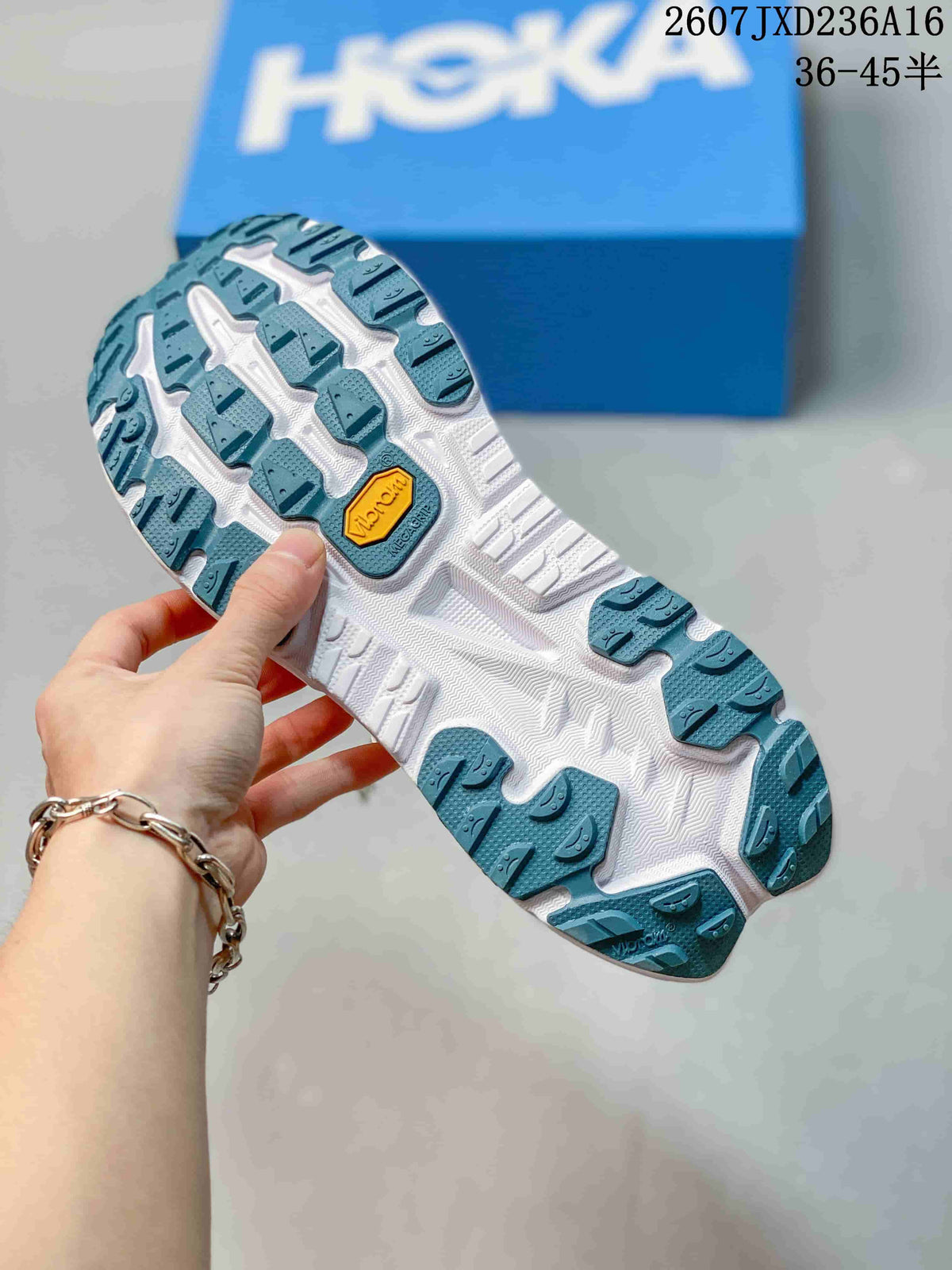 Underside view of the shoe showing the teal and white lugged outsole with visible Vibram branding.