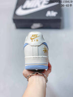 Rear view of the white sneaker showing gold-toned heel branding and a light blue outsole edge.