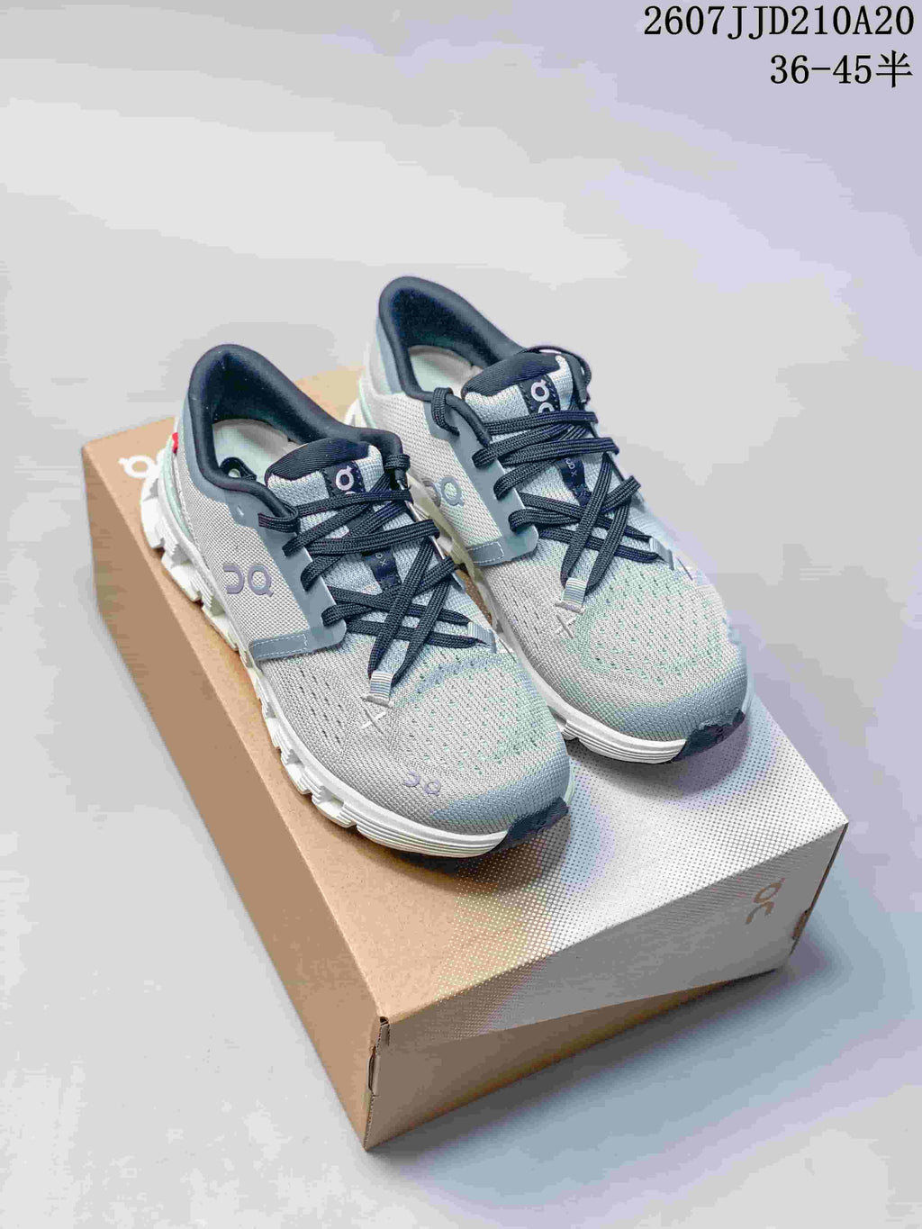 Gray On Cloud X4 sneakers with black laces shown on a shoe box; source text displays style code 2607JJD210A20 and size range 36–45.5.
