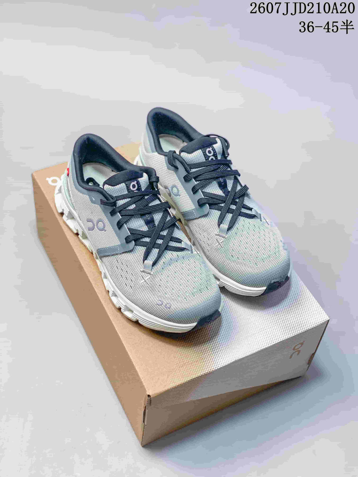 Gray On Cloud X4 sneakers with black laces shown on a shoe box; source text displays style code 2607JJD210A20 and size range 36–45.5.