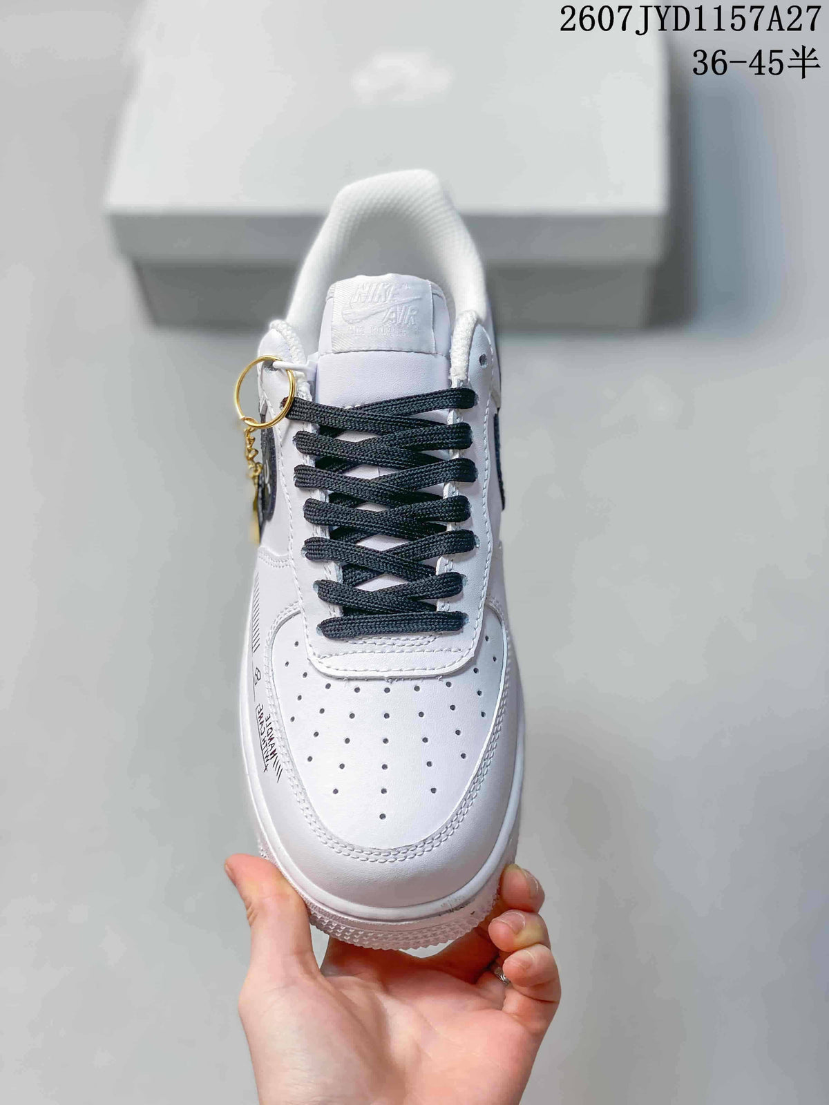 Top view of a white sneaker with black laces, perforated toe panel, and a white tongue label.