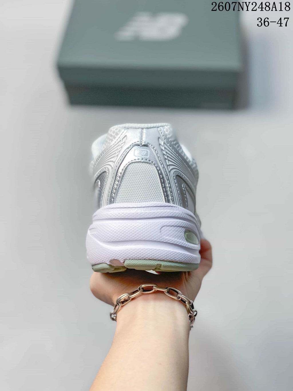 Rear view of the white and silver sneaker showing the padded heel and layered sole.