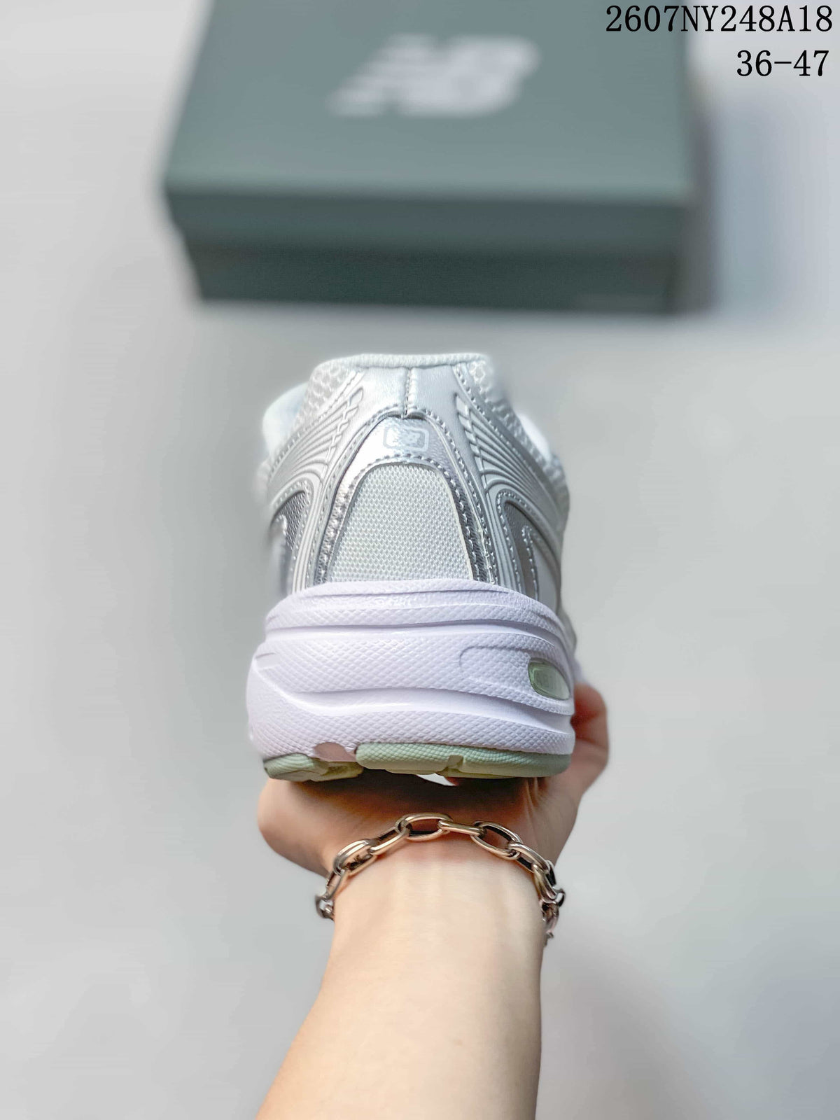 Rear view of the white and silver sneaker showing the padded heel and layered sole.