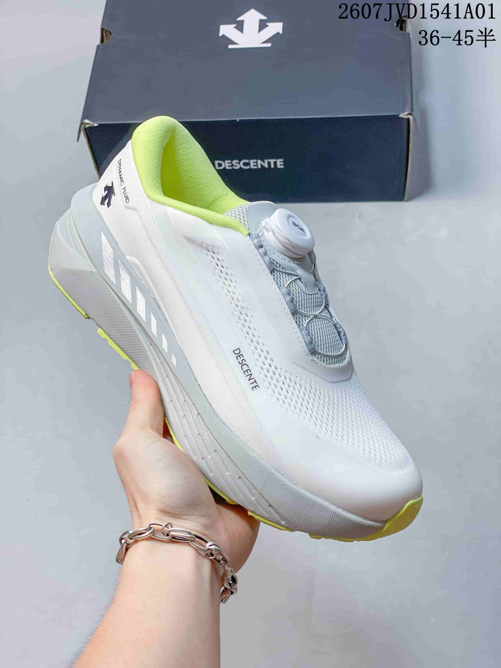 Side view of a white Descente running shoe with lime accents and dial closure.