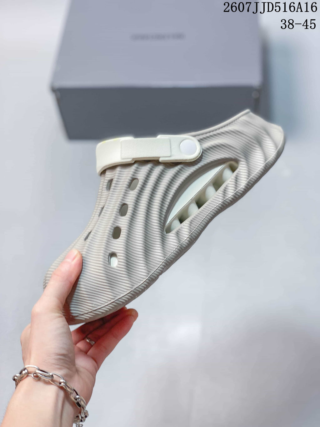 Side view of the clog showing the closed toe, wave-textured surface, ventilation opening, and heel strap.