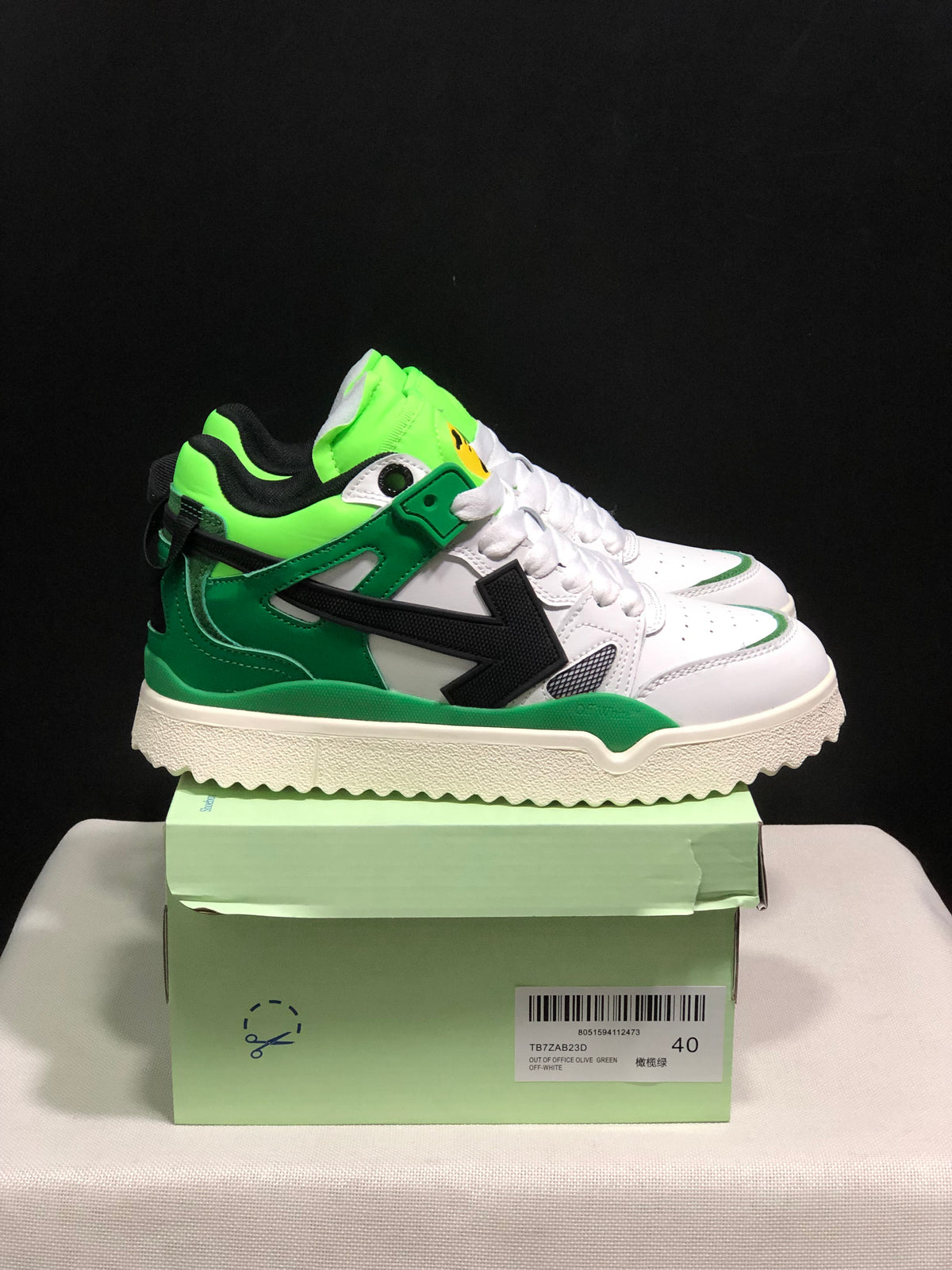 Side view of the sneakers showing the black arrow detail, green overlays, neon green collar, and cream textured outsole; the box label shows size 40.