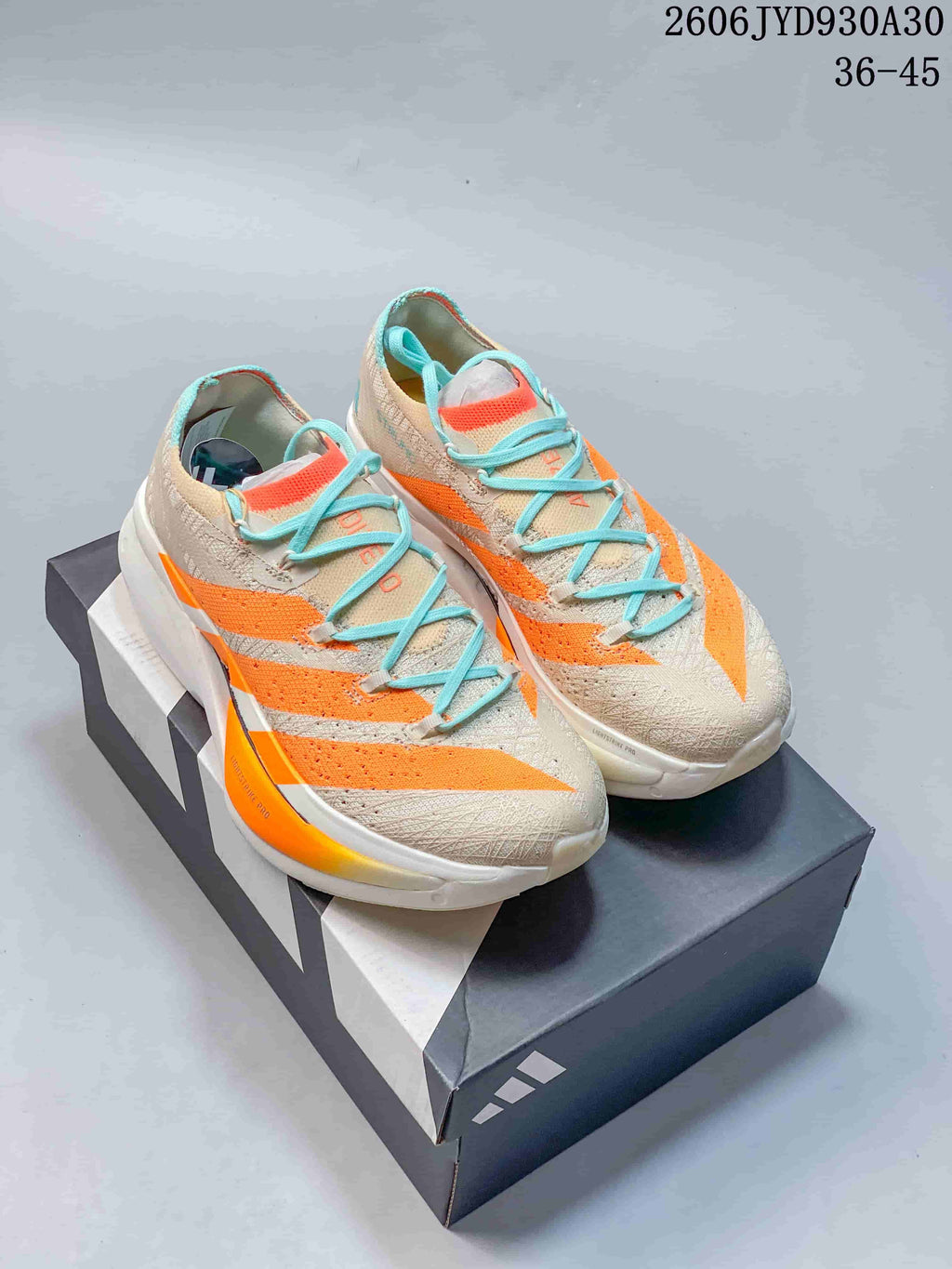 Pair of beige Adidas Adizero Prime X3 running shoes with orange accents and turquoise laces