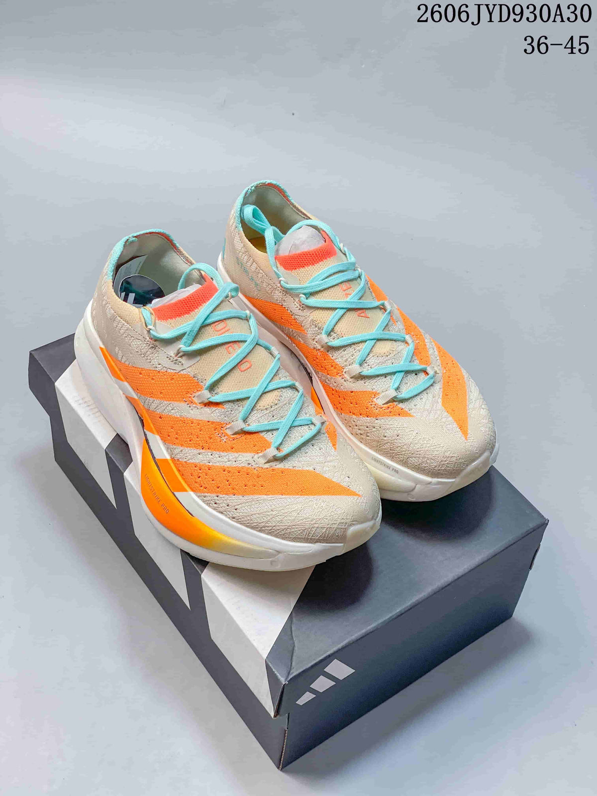 Pair of beige Adidas Adizero Prime X3 running shoes with orange accents and turquoise laces