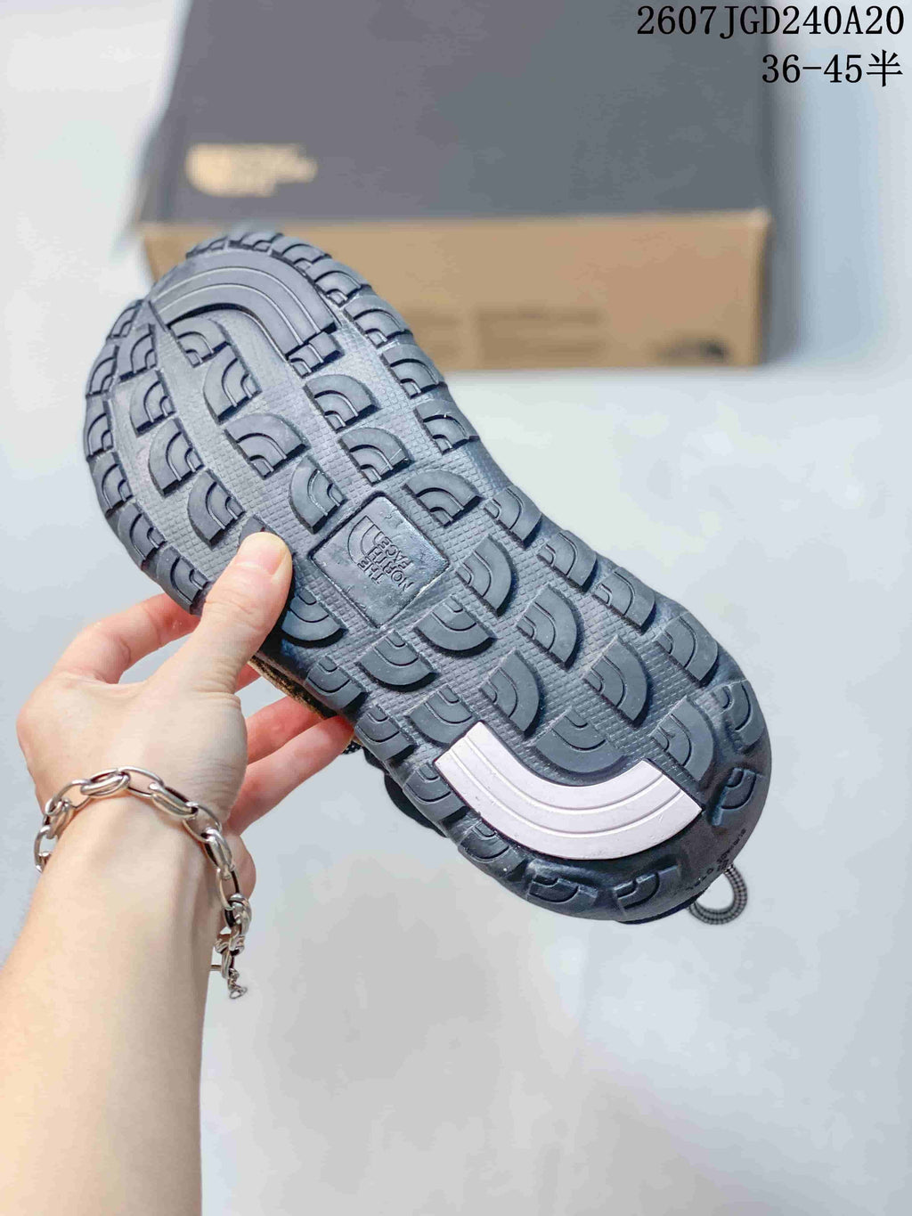 Close-up of the black patterned outsole showing its tread design and central branding detail.