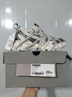 White and black sneaker displayed on a gray shoebox; the visible label shows style 0310, color WHITE/BLACK, and size E 40.
