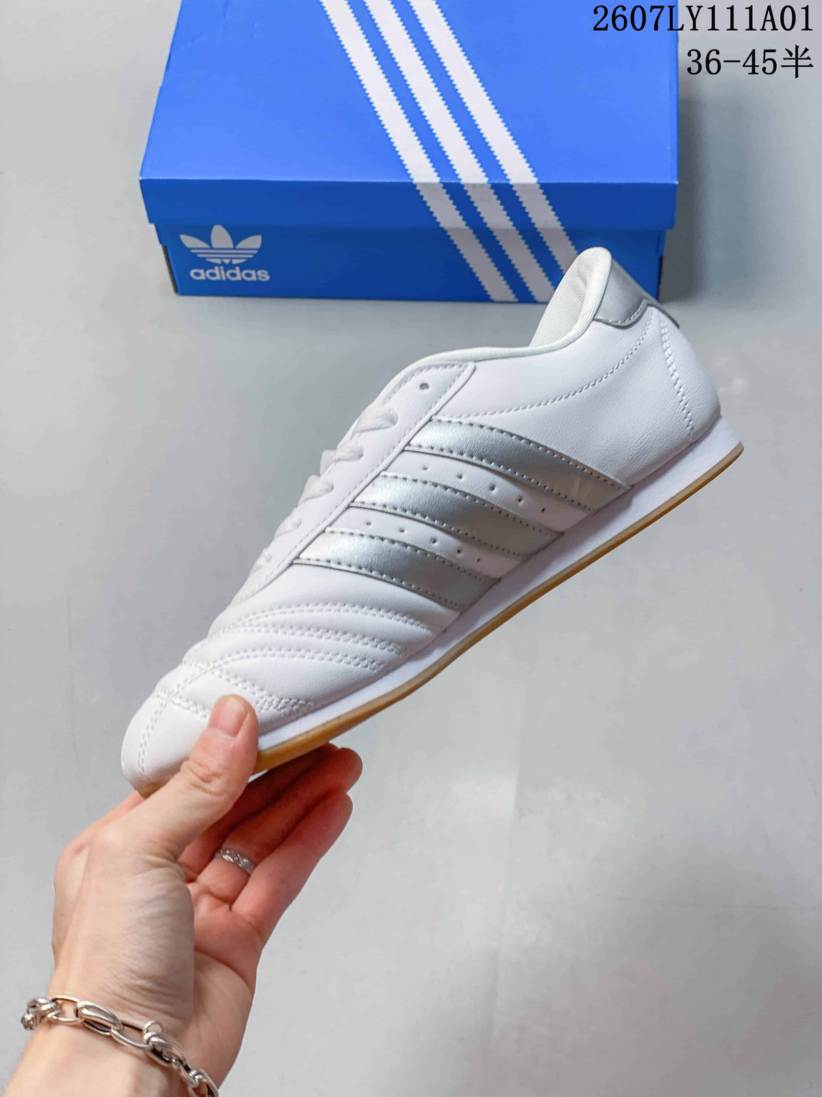 Side view of the white low-top sneaker with metallic silver stripes and a gum-colored outsole.