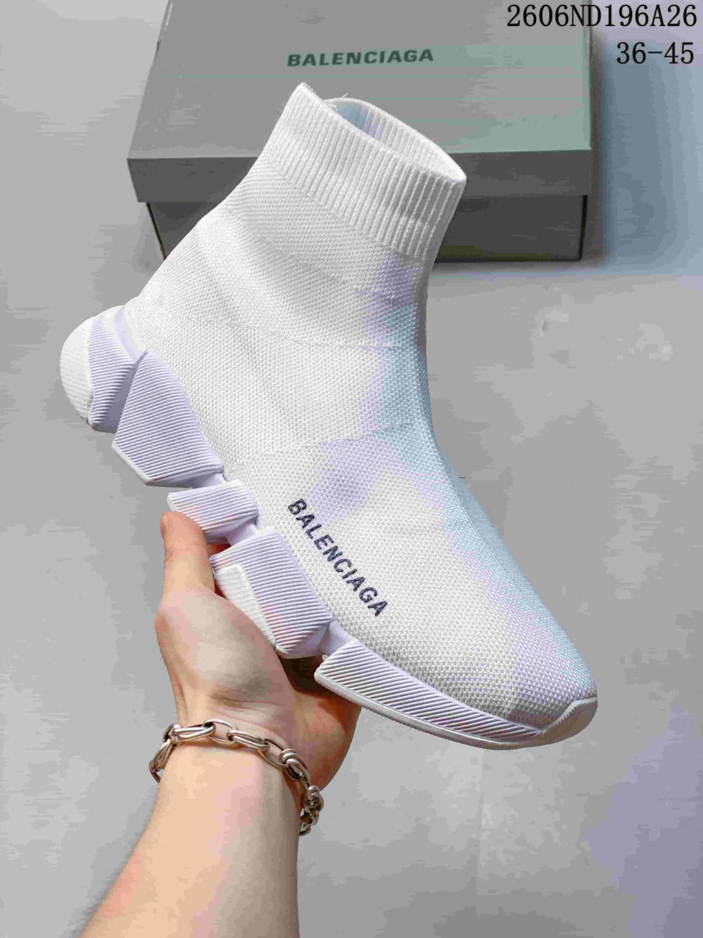 Angled side view of a white Balenciaga sock sneaker showing the high knit collar, side logo and segmented sole.
