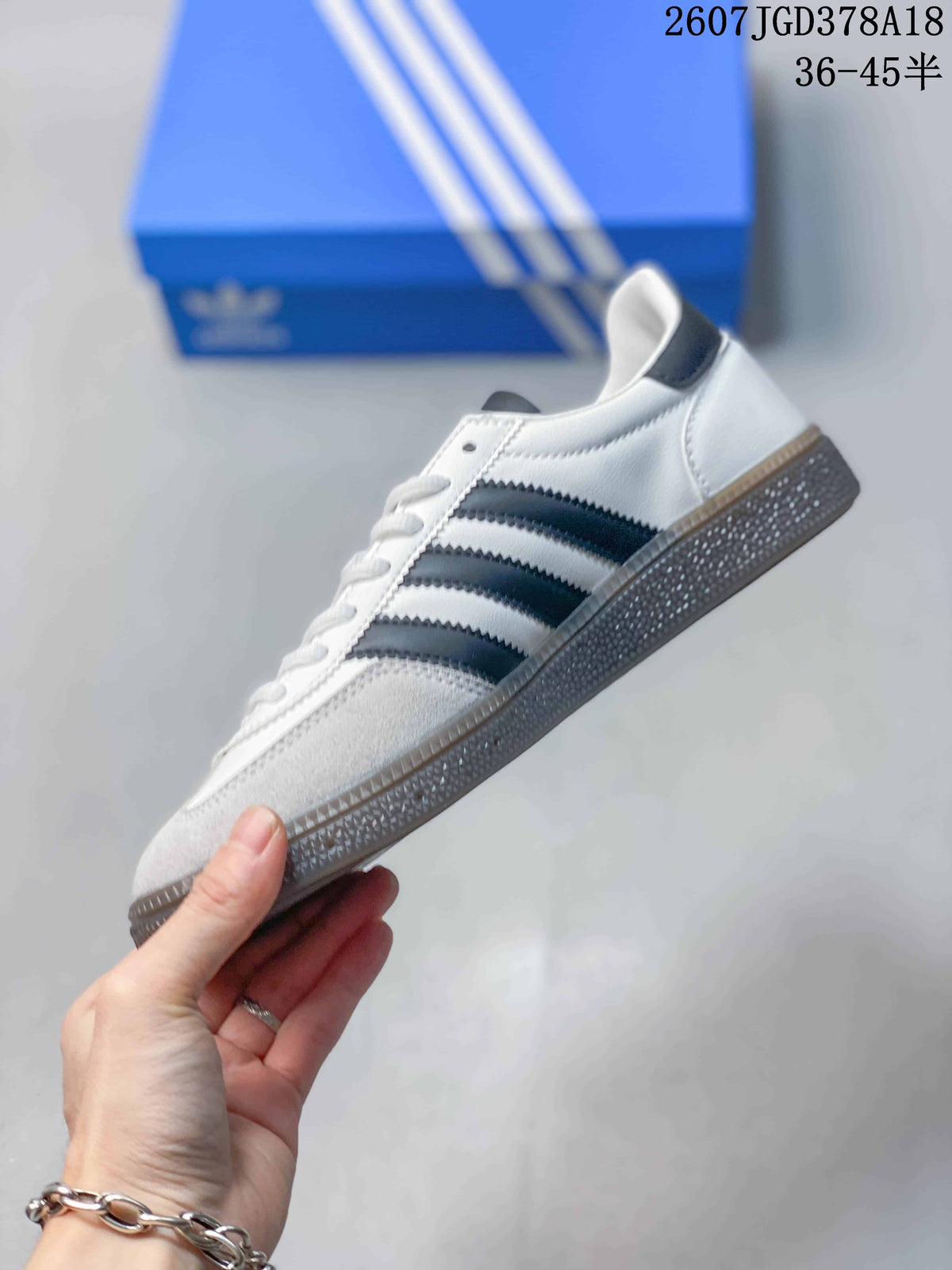 Side profile showing the white upper, three dark side stripes, and textured gray sole.