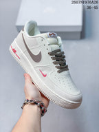Angled side view showing the white upper, brown Swoosh, red branding accents, and textured outsole.