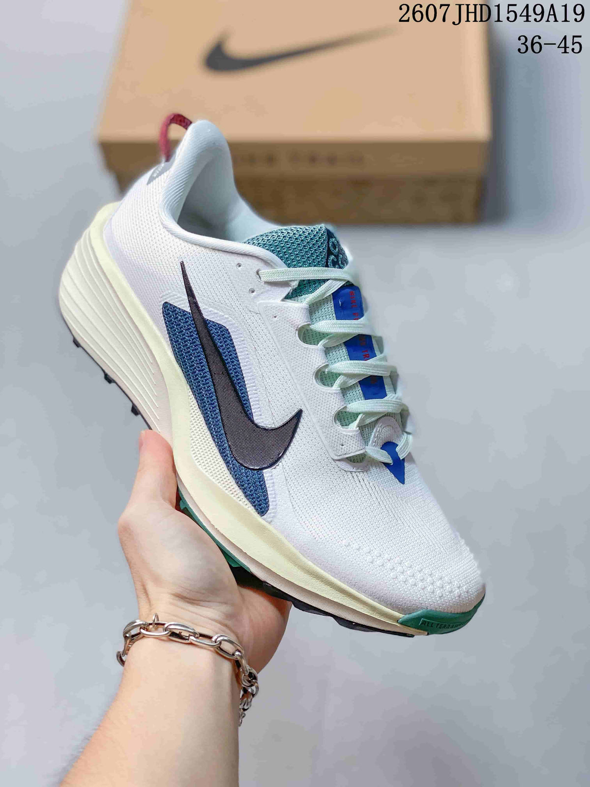 White Nike Zoom Fly 5 sneaker with a dark blue Swoosh, blue tongue details, and green outsole accents.