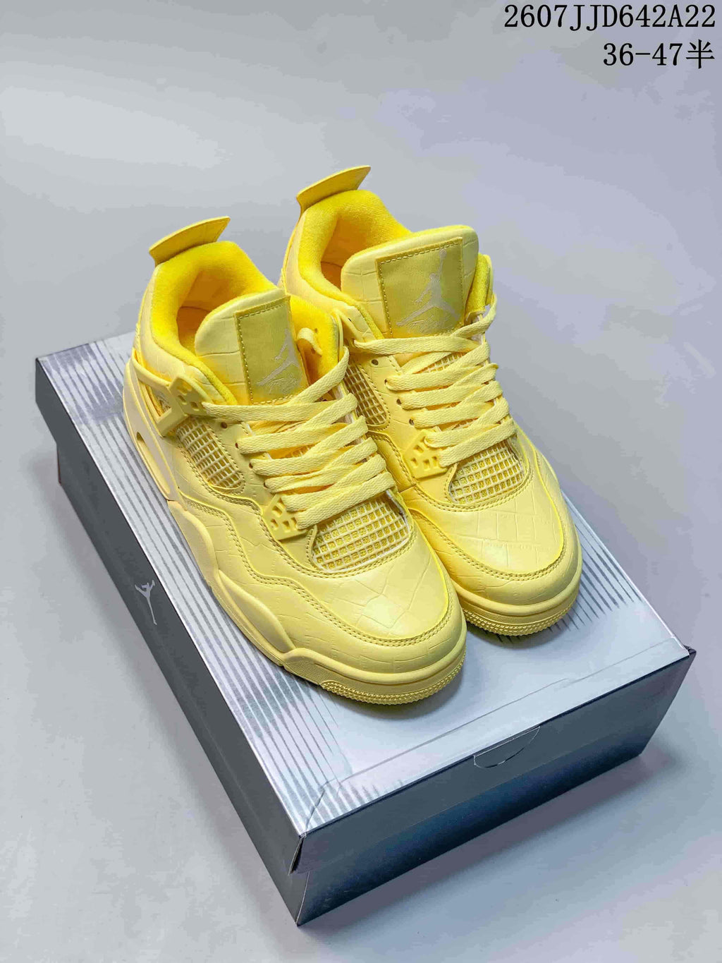 Pair of yellow high-top sneakers displayed on a shoebox, showing the front, laces, mesh panels and padded collars.