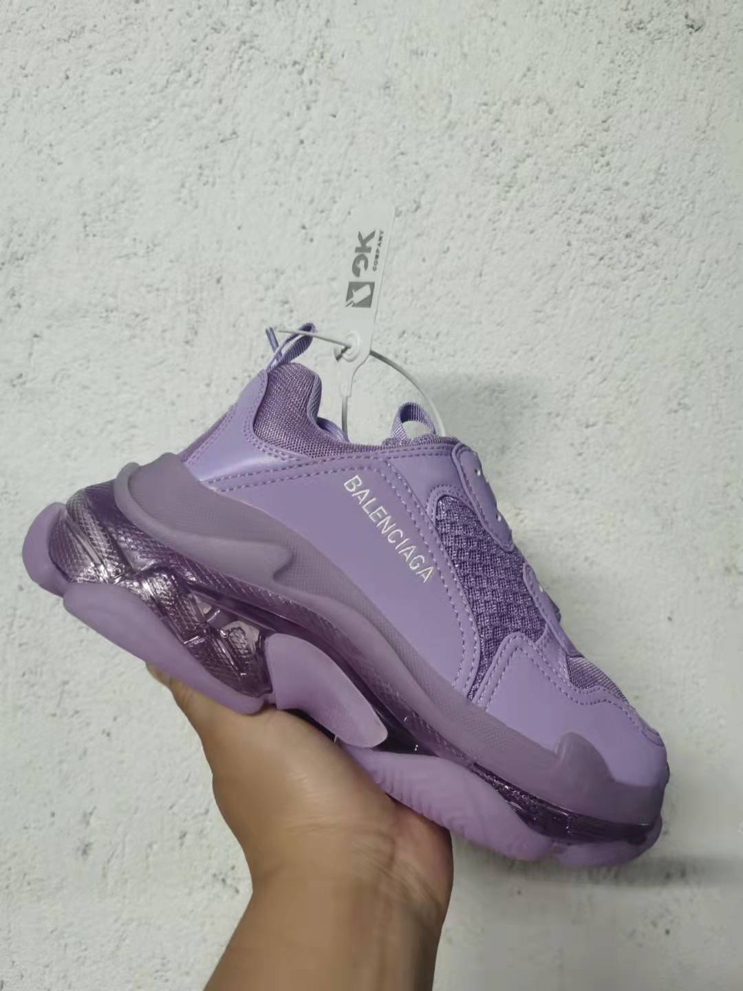Angled close view of the purple Balenciaga Triple S sneaker with visible side branding and textured panels.