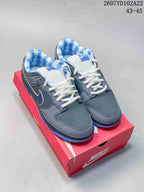 Pair of grey and blue Nike SB Dunk Low Pro sneakers displayed on a red shoebox, with white laces and blue patterned lining visible.
