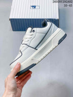 Side view of the white and navy low-top sneaker showing the layered upper, contrast trim, and raised sole.