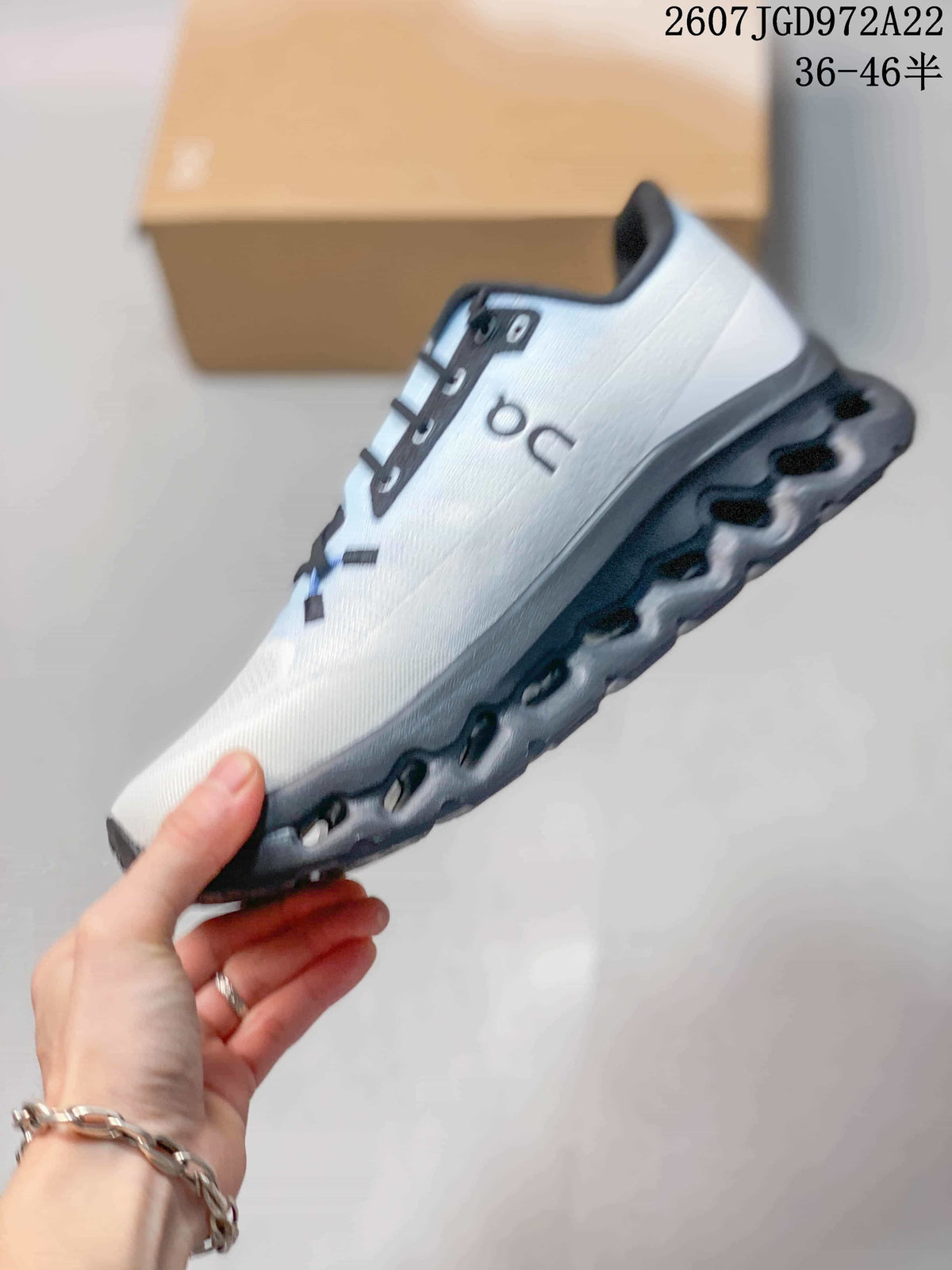 Side profile showing the white mesh-textured upper, black laces, On branding, and dark segmented sole.