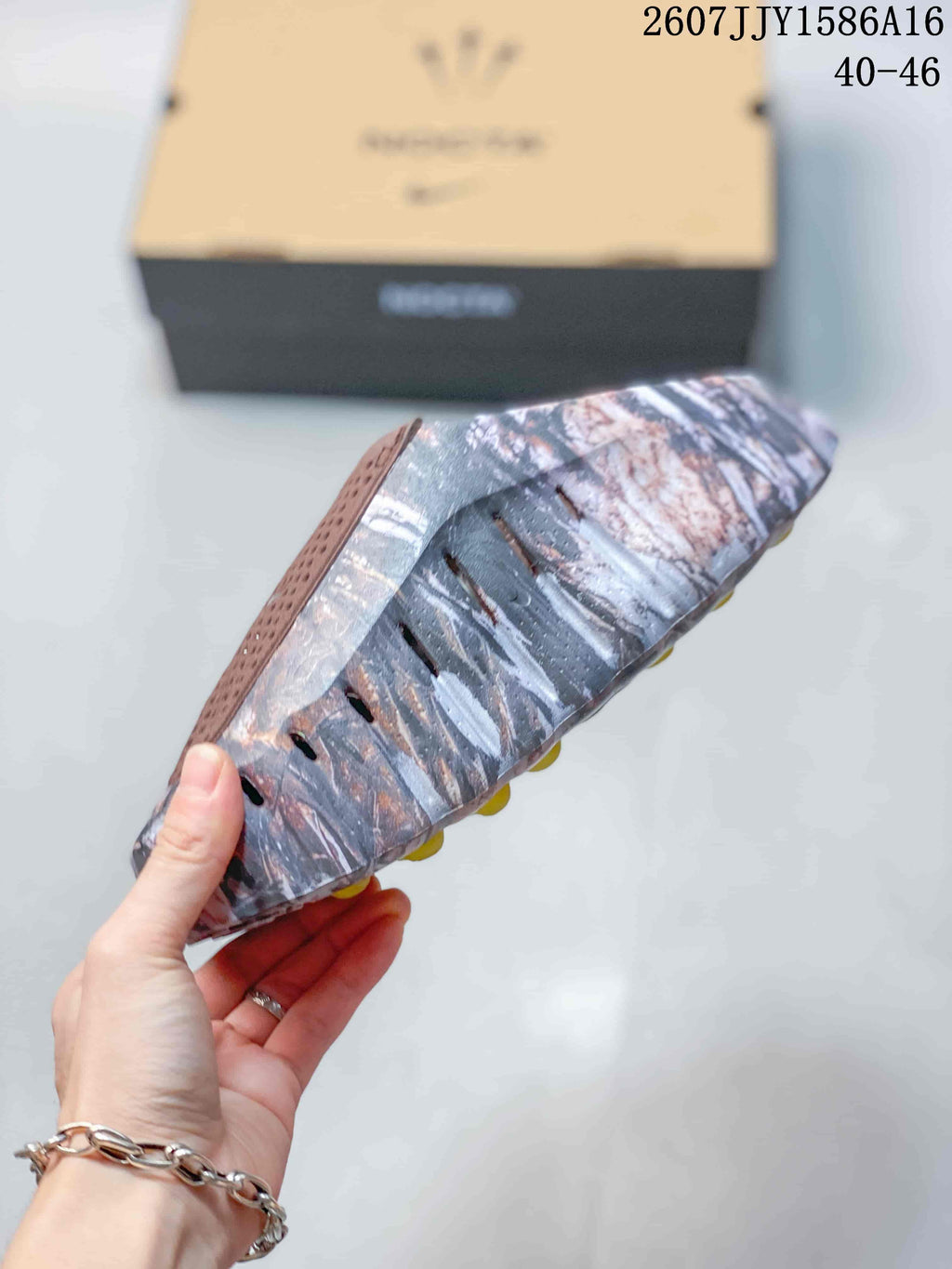 Side view of the marbled slip-on sandal showing the raised textured sole and brown perforated upper strap.