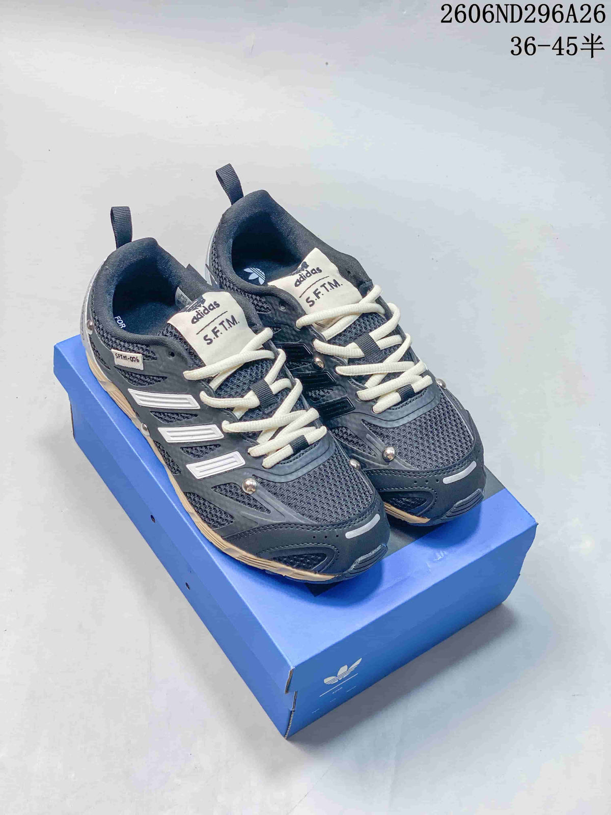 Pair of dark gray Adidas Originals S.F.T.M. low-top sneakers displayed on a blue shoebox.