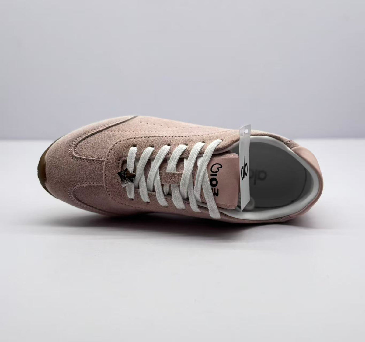 Top view of one sneaker showing the white laces, tongue branding, and pink upper.