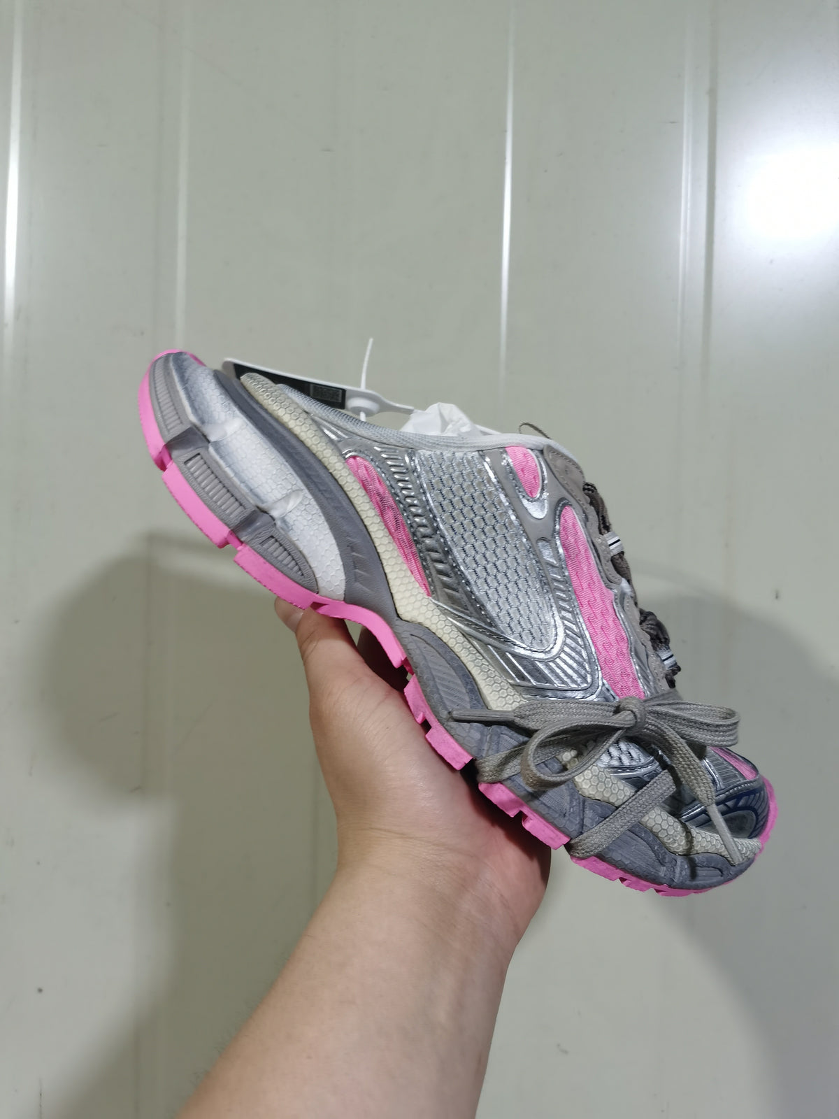 Angled front view of the grey and pink sneaker highlighting the layered upper, laces, and contrasting outsole.