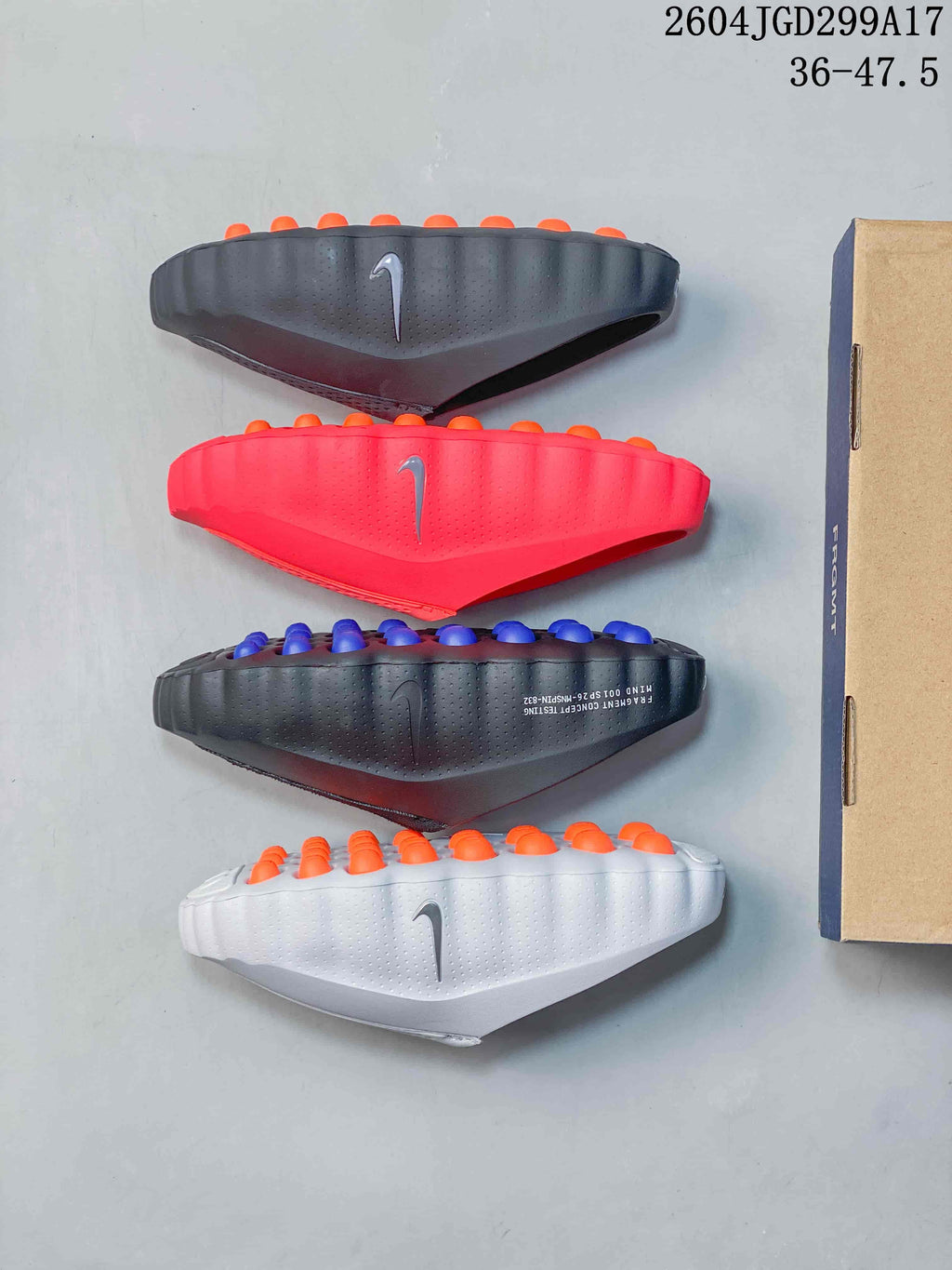 Four Nike Mind slide soles shown from the side in black, red, dark blue-gray, and white, with rows of circular outsole nodes.